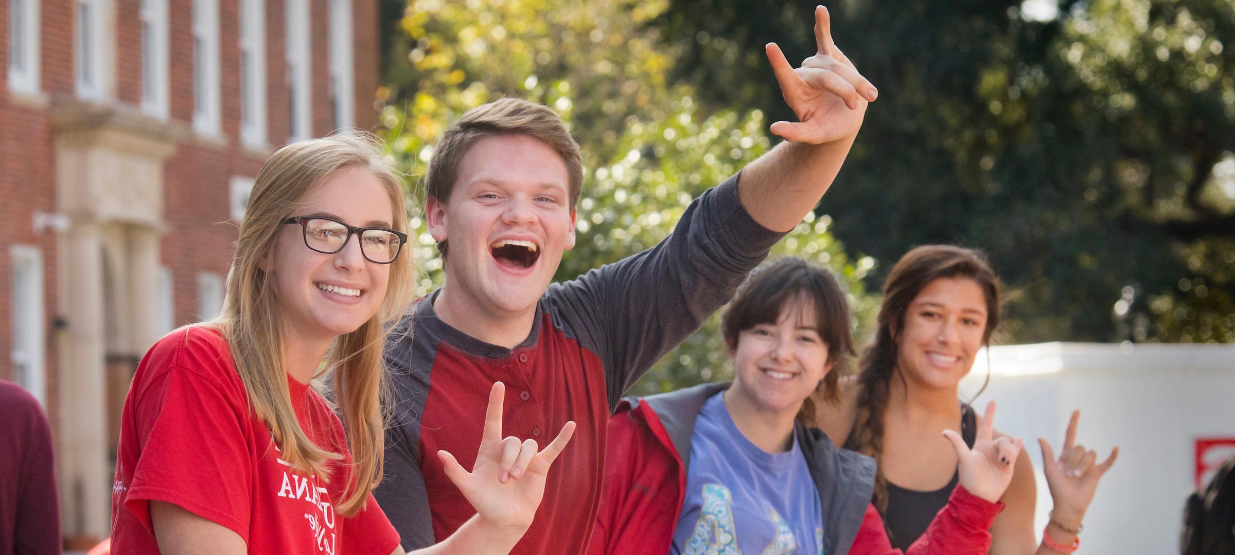 students smiling and making the UL hand sign