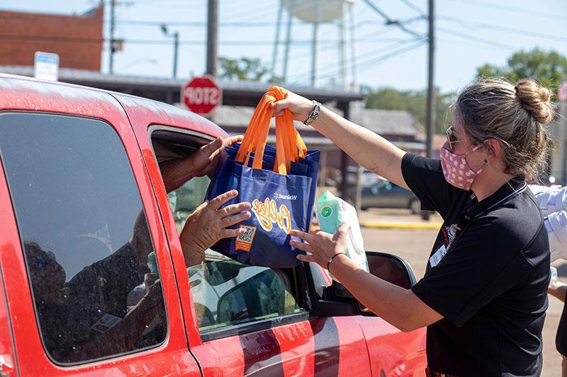 A UL Lafayette student hands donated groceries to a Louisiana resident in need