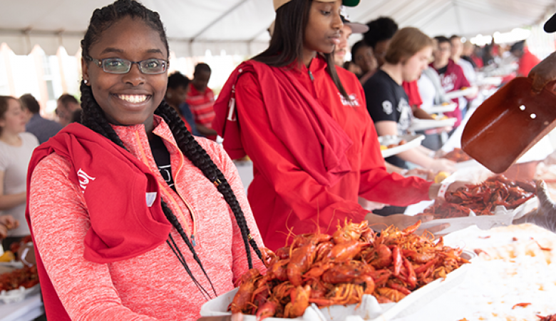 拉斐特大学的学生穿着红色套头衫，手里拿着一盘小龙虾